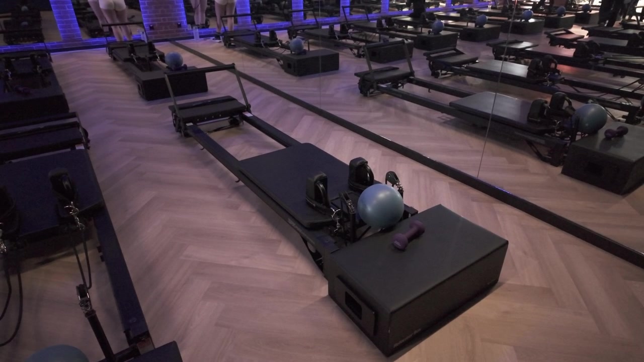Pilates reformers and exercise equipment stand ready before fusion workout class