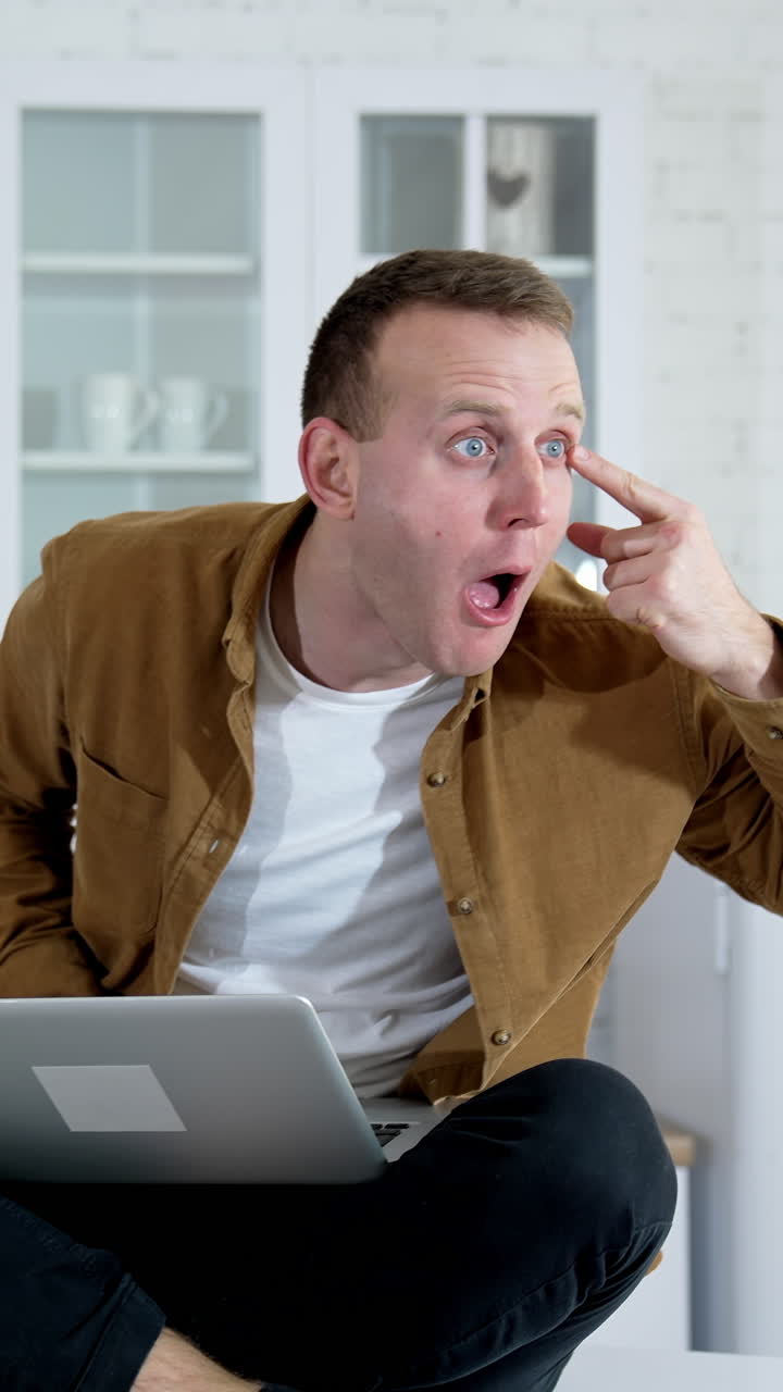 Funny man playing with his eye. Portrait of young adult amazed looking at camera. Vertical video