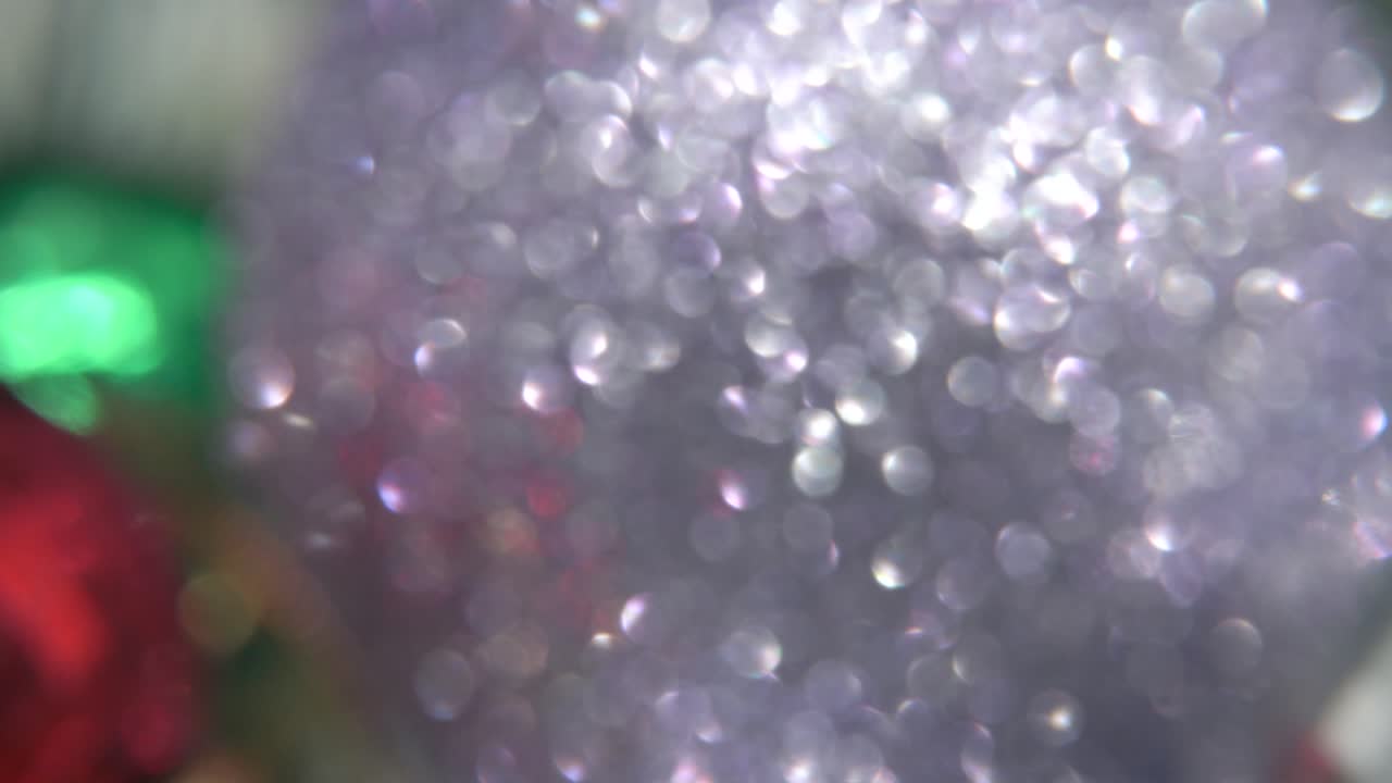 decoración de navidad, coloridos adornos de cristal bolas coloridas en un soporte giratorio 360 año nuevo decorado, luces brillantes, cinematográfico close-up macro tilt up video 4k, hermosa profundidad de campo