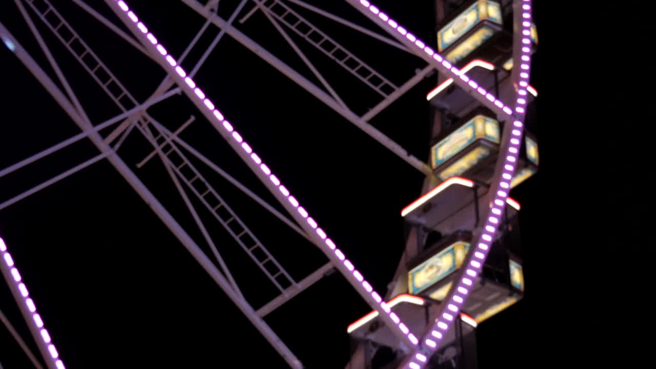 primer plano de la noria giratoria iluminada en el parque de atracciones