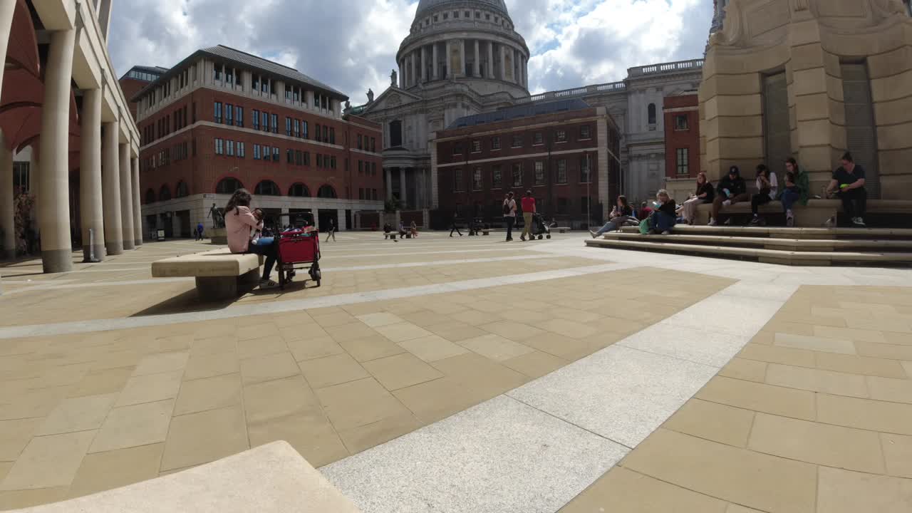 런던의 파터노스터 스 ⁇ 어 (paternoster square) 를 돌아다니는 사람들의 시간 흐름, 세인트 폴스 (st. pauls) 를 배경으로 볼 수 있습니다.