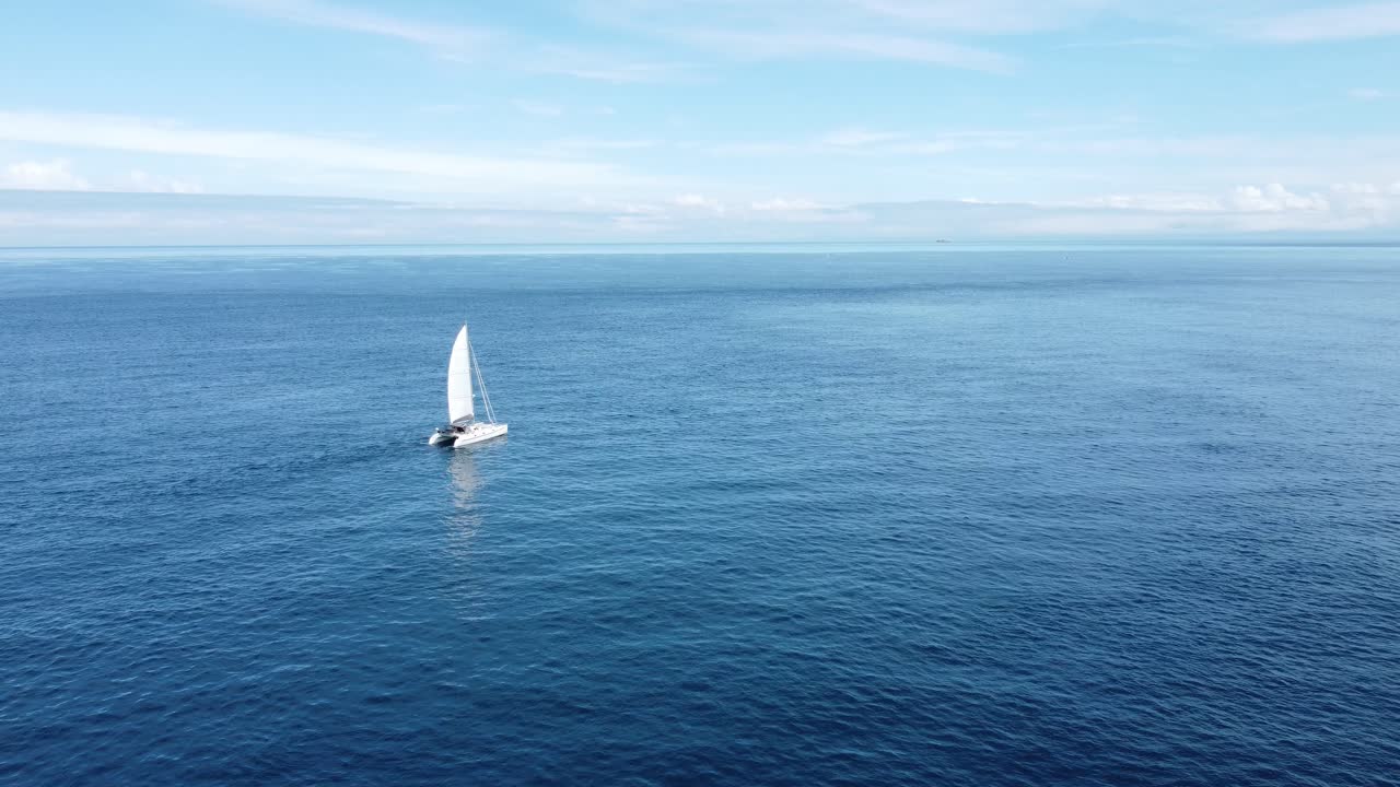 volando hacia un pequeño yate mientras navega lentamente a través de un océano plano