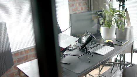 Close-up-of-desk-with-computer,-laptop-and-microphone-at-home,-slow-motion