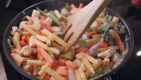 verduras congeladas añadidas a la sartén caliente con pollo y cebollas