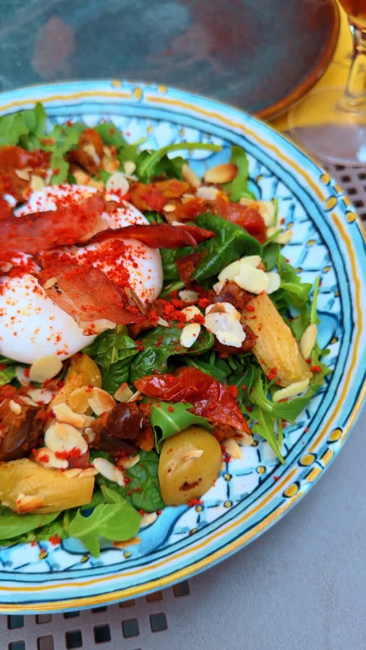 Gourmet burrata salad with arugula and sun-dried tomatoes. Top view of fresh cheese salad with nuts and spices served on ornamental blue ceramic plate