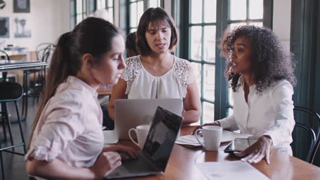 businesswomen having informal meeting around table in coffee shop