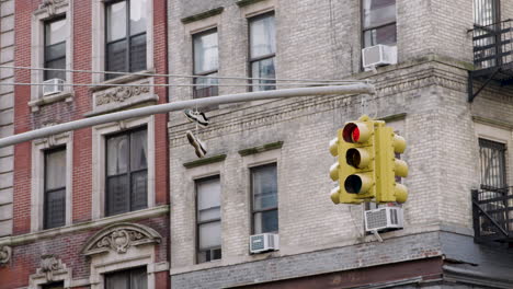 sneakers on traffic signal with new york city apartment buildings in background