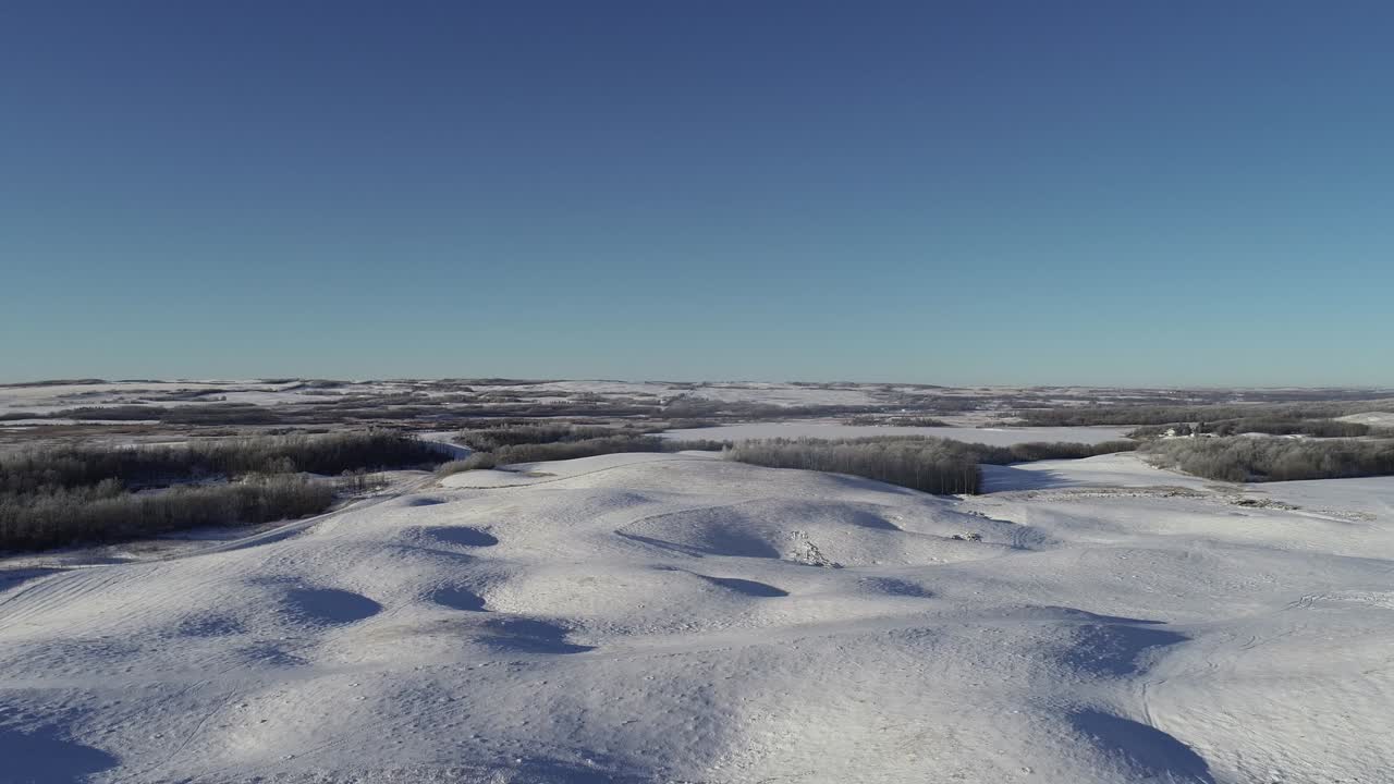 Sorvolo di droni a media quota di dolci colline coperte di neve.