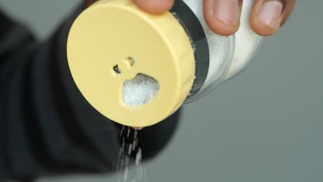 close-up of a hand pouring salt from a shaker