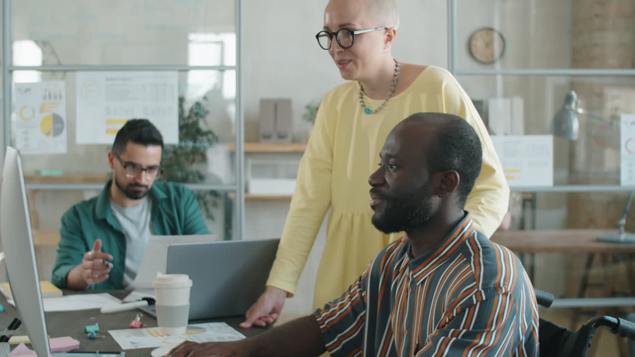 African American Businessman with Disability Working with Female Colleague in Office