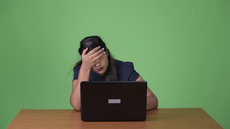 young overweight beautiful indian businesswoman against green background