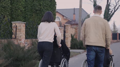 rear view of woman and man taking a walk with her disable friends in wheelchair around the city