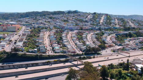 San-Francisco-southern-freeway-aerial-view-following-busy-traffic-driving-under-neighbourhood-rows-of-California-homes
