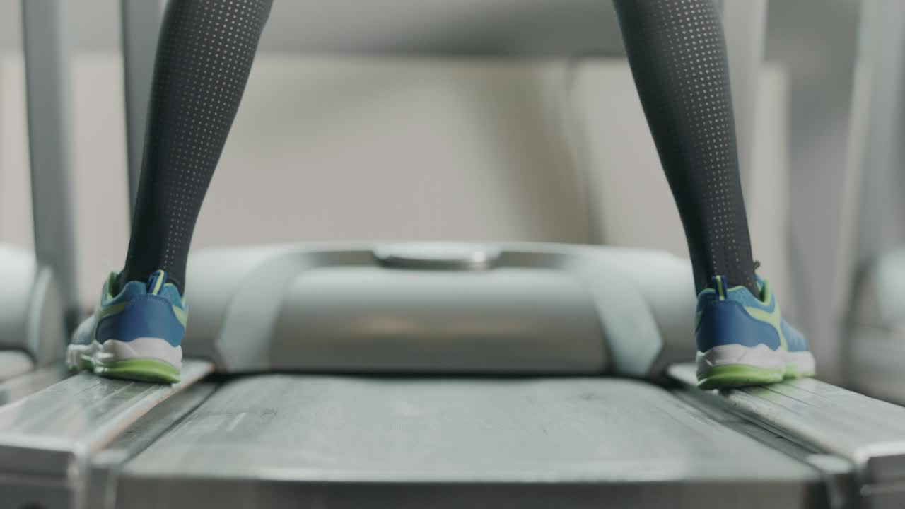 Closeup athletic feet running on running machine in fitness gym.
