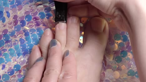 4k top-down footage of woman trimming toenails over shiny sequin-covered fabric