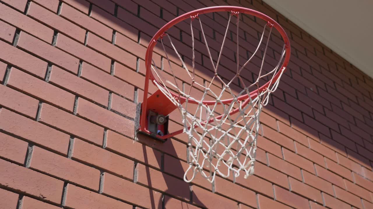 primer plano de un aro de baloncesto con una bola que rodea un aro de metal y entra en la red para marcar un gol