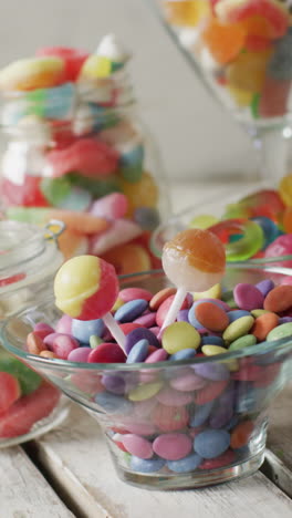 video of colourful various sweets in glass vessels on wooden table