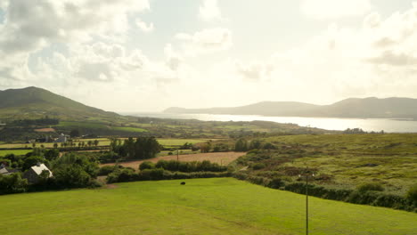 low aerial shot over irish farmland towards the sea