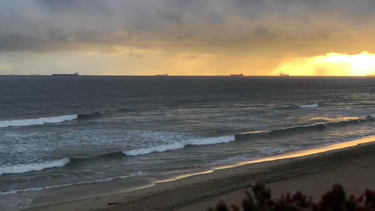 4k 60p, puesta de sol dorada en el océano con buques de carga en el horizonte