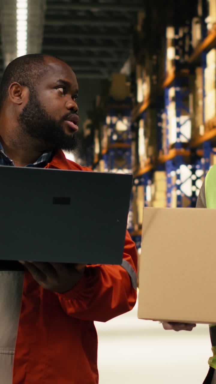 Video verticale. Colleghi sistemano scatole di cartone sugli scaffali ed effettuano l'inventario tramite laptop.