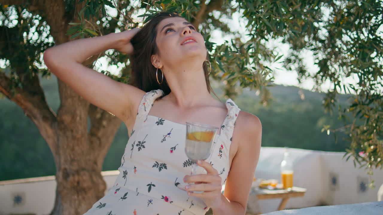 Ragazza spensierata che contempla la natura, toccandosi i capelli in terrazza, primo piano. Siesta della signora.