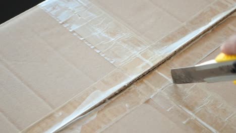 close up of a cardboard box being opened with a utility knife