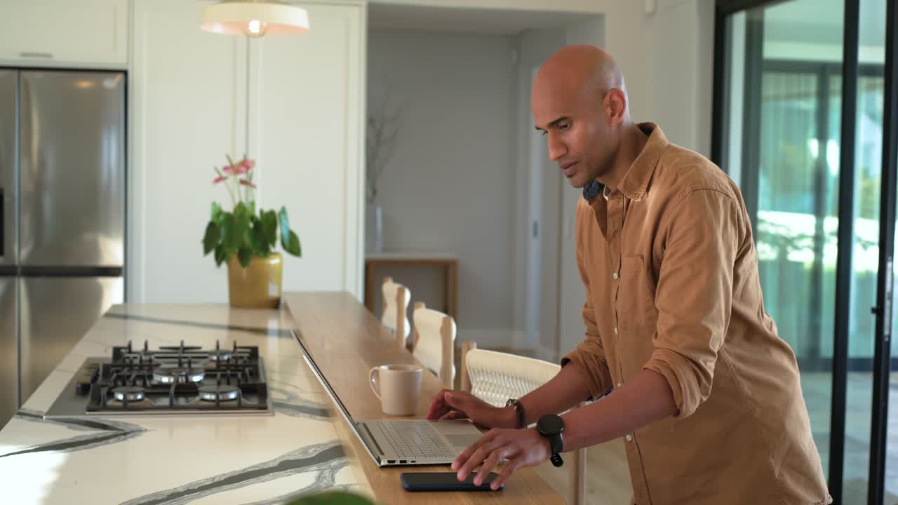Checking laptop in kitchen, man sipping coffee before typing email and calling client, copy space