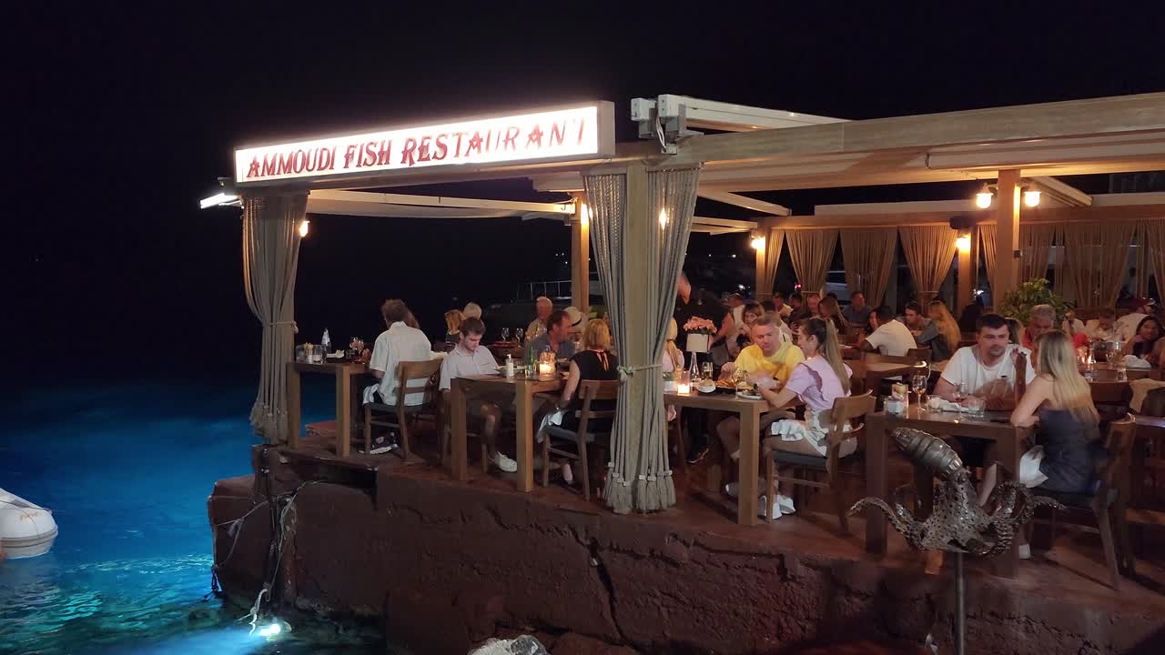 Nighttime dining experience at Ammoudi Fish Restaurant overlooking the water