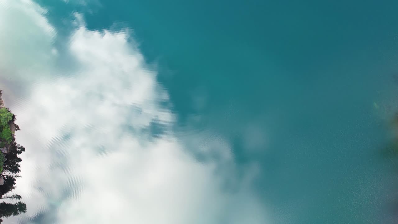 un dron aéreo captura la belleza serena de un lago con el cielo reflejado en sus aguas onduladas