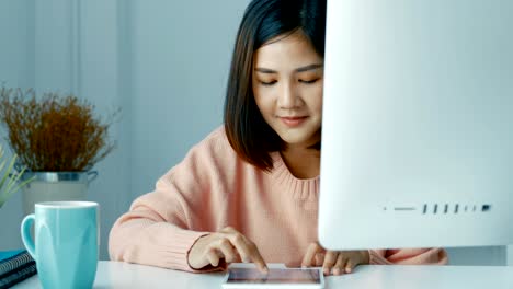 젊은 아시아 여성 사업주들이 스마트폰 앱을 사용하고 사무실에서 주식 시장에서 놀고 있습니다.