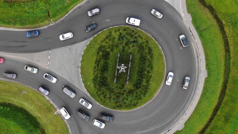 cars drive along large circular crossroad in rural area