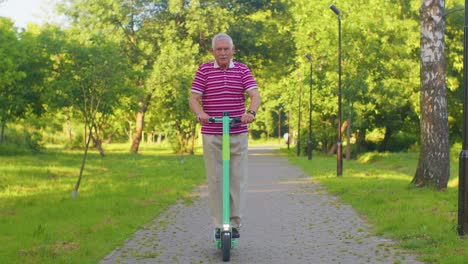 Abuelo-Hombre-Mayor-Y-Elegante-Montando-Scooter-Eléctrico-En-El-Parque,-Abuelo-Moderno-Conduciendo-Vehículo-Urbano