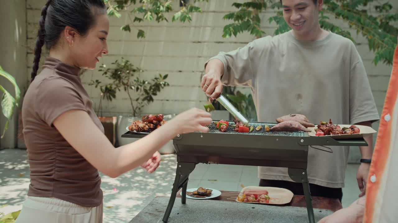 Girl Giving Grilled Kebab to Boyfriend during Outdoor Party