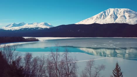 4k drone video of snow covered lakeside mountains in alaska during winter