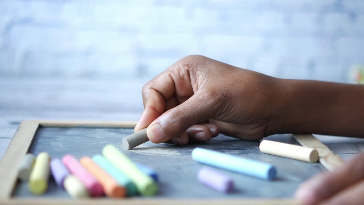 Hand holding chalk on a chalkboard