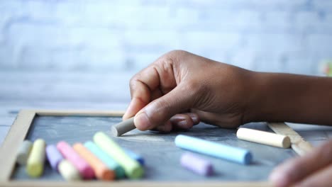 hand holding chalk on a chalkboard