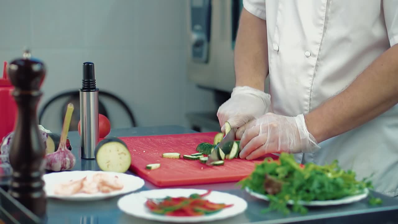 el cocinero corta un pepino fresco para una ensalada con un cuchillo