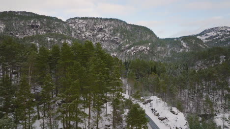 drone shot flying over snow covered trees in the mountains of norway