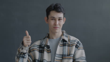 young man smiling and giving a thumbs up