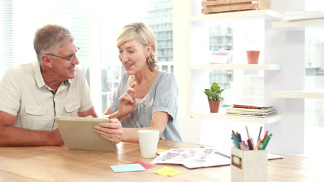 Smiling-casual-colleagues-using-digital-tablet-in-office