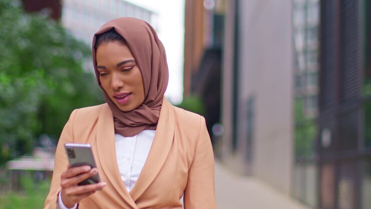Close Up Of Modern Muslim Businesswoman Wearing Hijab Walking On Way To Work In Office Looking At Mobile Phone 2