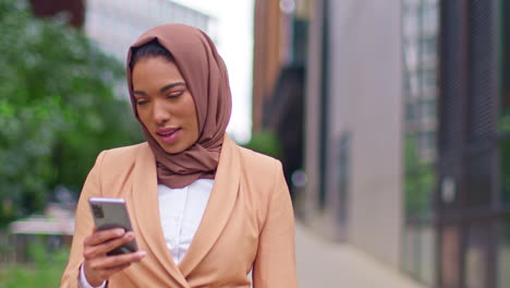 Close-Up-Of-Modern-Muslim-Businesswoman-Wearing-Hijab-Walking-On-Way-To-Work-In-Office-Looking-At-Mobile-Phone-2