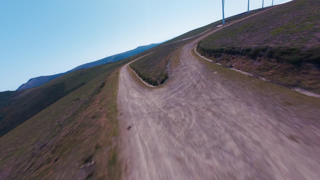 Voo em FPV em um parque eólico de alta montanha, serpenteando entre turbinas e cavalos selvagens correndo em terreno aberto, combinando natureza bruta, altitude e energia limpa em uma paisagem cinematográfica