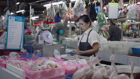 woman weighing chicken at a fresh market