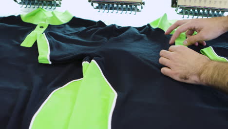 man in a textile factory checking the sewing on t-shirt