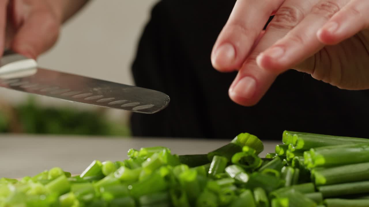 Cutting fresh green onions on a cutting board, close up chef cooking green vegan salad.