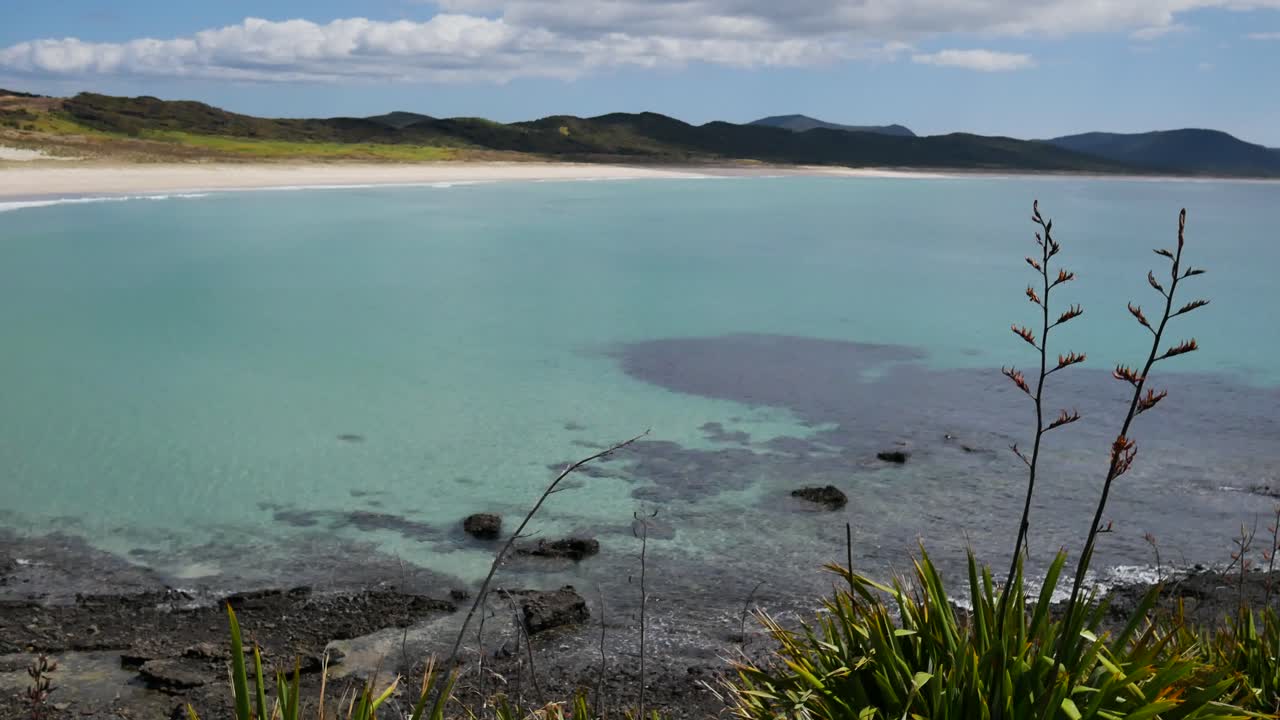 Panorama shot of empty paradise of Spirits Bay In New Zealand. Sandy beach,crystal clear water and mountains in background during sunny day
