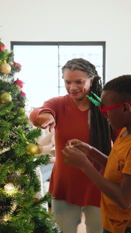 vertical video: decorating christmas tree, family celebrating festive holiday tradition in living ro