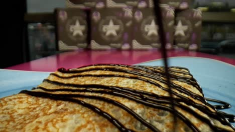 extreme close up pouring chocolate over a crepe