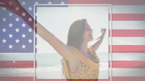 American-flag-with-glitch-effect-against-woman-standing-with-her-arms-wide-open-at-the-beach